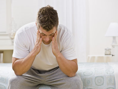 Tired Man Sitting on Bed